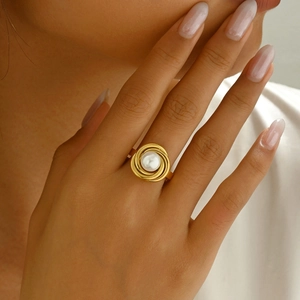 Detail of a luxury gold spiral ring with a central pearl on model's finger