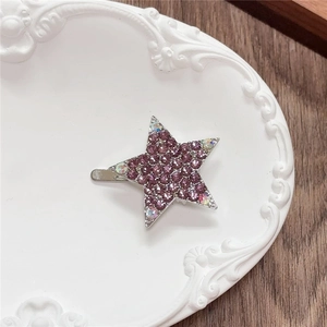 Detail of star-shaped hair clip with purple rhinestones on a vintage white tray