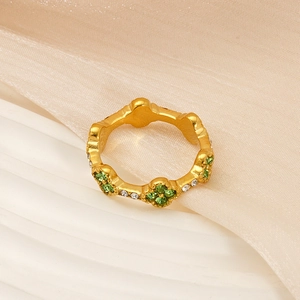 Macro detail of 18K gold flower ring with green and clear cubic zirconia stones