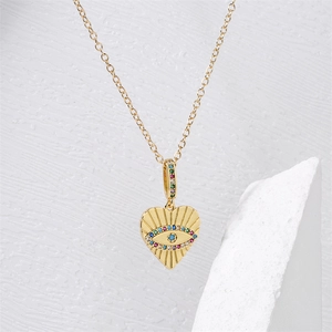 Gros plan du pendentif cœur mauvais œil avec zircons colorés sur une chaîne dorée