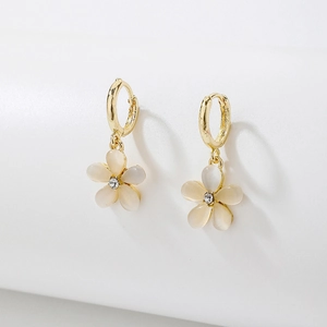 Close-up of golden flower earring with cat eye petals and center crystal detail