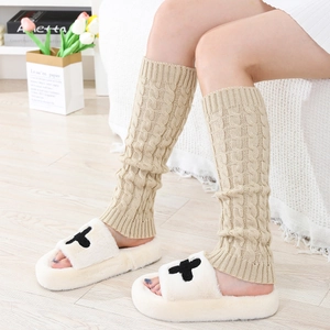 Detailed close-up of beige cable knit leg warmers with soft wool texture and elastic cuffs