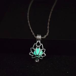 Detailed close-up of a silver lotus locket necklace with a glowing green inner bead