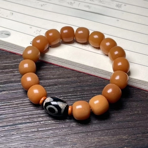 Detailed view of beaded Dzi bracelet with orange agate beads on vintage calligraphy paper