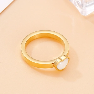 Detail view of a gold wide-band ring featuring a polished white cat-eye stone heart