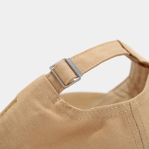 Détail de la casquette de baseball beige avec boucle métallique réglable et coutures