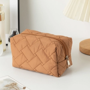 Detail view of brown quilted cosmetic bag with soft texture and silver zipper finish