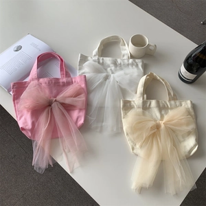 Flache Ansicht von Canvas-Taschen mit Tüllschleifen in Rosa, Weiß und Creme