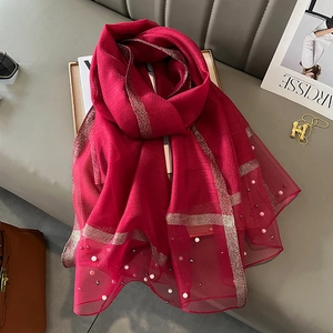Detail of red mesh shawl featuring gold silk stripes and delicate white pearl beadwork