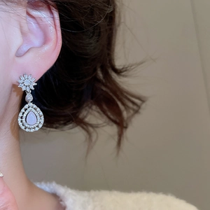 Gros plan de boucles d'oreilles poire roses avec détails floraux en zircon sur mannequin