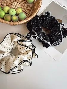 Close-up of black and white polka dot hair scrunchies with wavy pleated edge texture