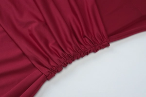 Detailaufnahme der Raffung und des seidigen Stoffs am weinroten Bodycon-Kleid