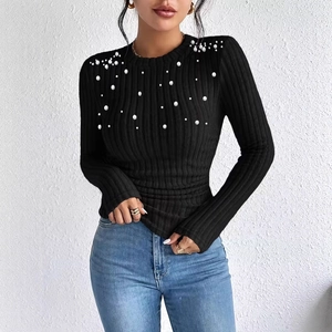 Detailed close-up of pearl embellishments on a black ribbed knit long sleeve top