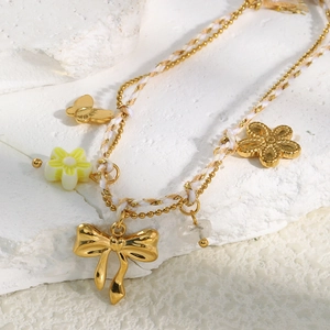 Detail of 18K gold plated bracelet with white cord, bead chain and floral charms
