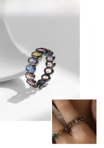 Macro detail of multi-colored gemstones set in black gold plated silver ring band