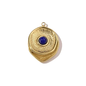 Close-up of golden sunburst pendant with central blue stone on white background