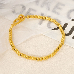 Detailed view of the gold-toned beaded chain bracelet with a unique OT toggle closure
