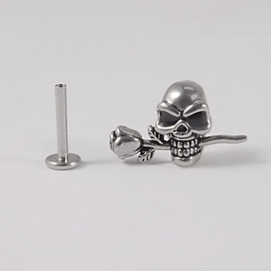 Detail of silver skull and rose surgical steel ear stud with high-gloss finish