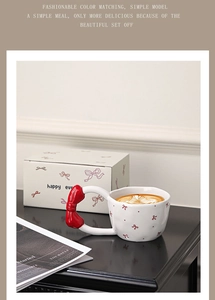 Detailed close-up of a white ceramic mug with red bow handle and matching gift box