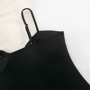 Detail of black bodysuit featuring adjustable straps with metal buckles and padded cups