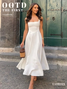 Robe midi blanche élégante avec col carré et jupe évasée dans un décor de vacances