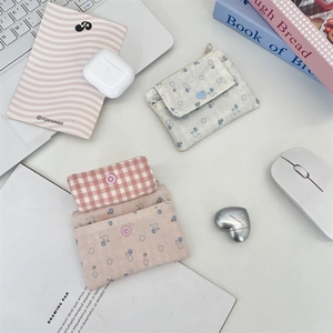 Porte-cartes en tissu à fleurs et carreaux disposés sur un bureau avec des accessoires