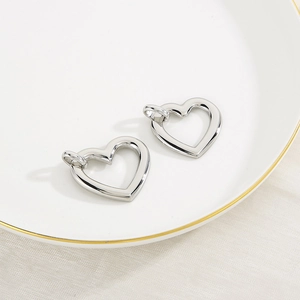 Macro view of polished silver hollow heart pendants on a decorative white ceramic plate
