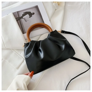 Detail of black pleated cloud bag with vintage brown wooden handle and gold hardware