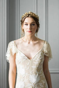 Detail of bridal champagne dress with floral embroidery and golden leaf headpiece