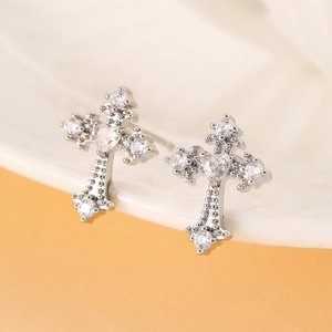 Minimalist silver cross stud earrings with white cubic zirconia on white ceramic edge