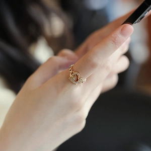 Close-up of luxury gold-finish interlocking double heart ring with crystal inlay on finger