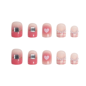 Pink checkered heart press-on nails with rhinestones and pearls on white background