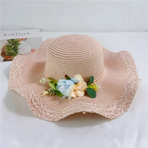 Detailed close-up of light pink straw hat with wave brim and delicate floral decoration