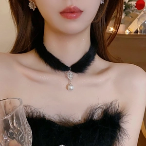 Détail d'un choker en peluche noire avec pendentif flocon argenté et perle blanche