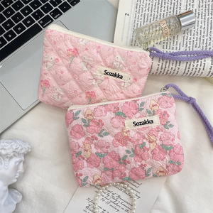 Detailed view of quilted floral makeup bags with cute rabbit patterns and zipper closure