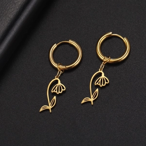 Macro view of gold stainless steel flower hoop earrings on a black textured background