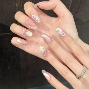 Pink cat-eye press-on nails with 3D floral accents and almond shape on hands