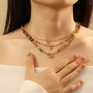 Detailed close-up of a three-layer necklace with colorful beads and golden ring clasp