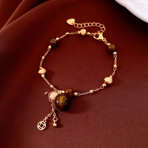 Detail of tiger eye beads with hollow metal ball and coin pendant on silk background