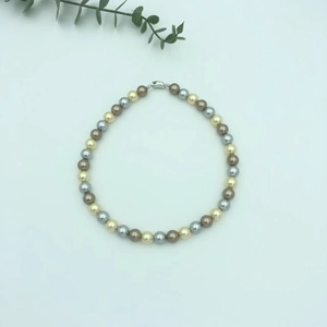 Detail of multi-color pearl necklace with champagne and grey tones and metal clasp