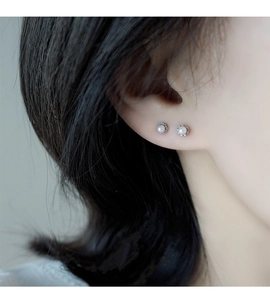 Macro detail of mini pearl screw-back stud earrings with silver bead edge on ear