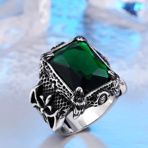 Macro shot of emerald-cut green stone with gothic dragon relief on stainless steel ring