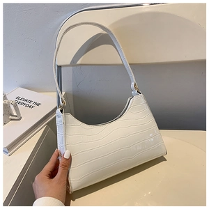 Detailed close-up of white crocodile pattern shoulder bag on a minimalist chair