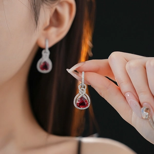 Dettaglio ravvicinato di orecchini in argento con zirconi e pietre rosse a triangolo