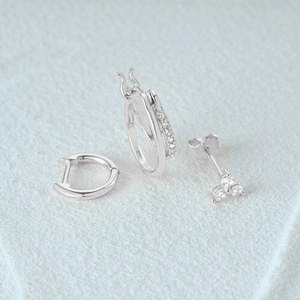 Close-up of a 3-piece set featuring silver geometric hoop earrings and stud with small crystals