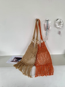 Detail of bohemian woven cotton bag with wooden handles and stylish fringe tassels