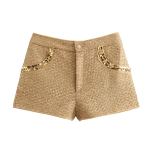 Close-up of golden tweed shorts with sparkling sequined flower detail on the pocket