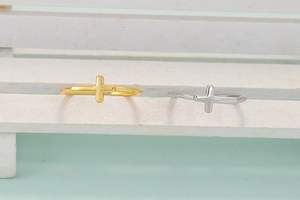 Minimalist adjustable cross rings in gold and silver finish on a textured background