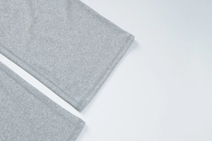 Detailed view of the fine flat-lock stitching on heather grey knit pants hem