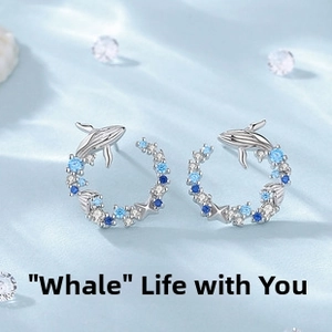 Detail of silver whale hoop earrings with blue and white cubic zirconia on silk